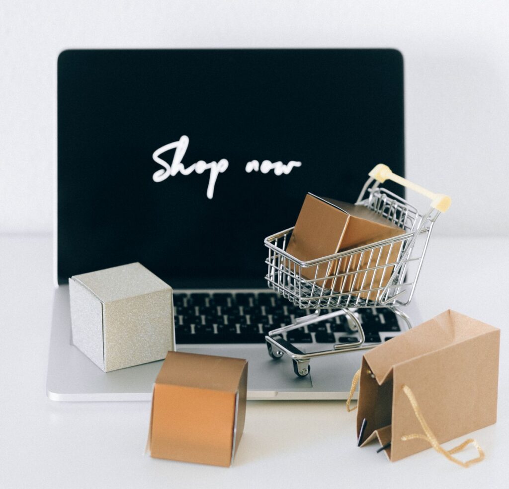 Minimalist online shopping setup with laptop, cart, and packages symbolizing e-commerce.